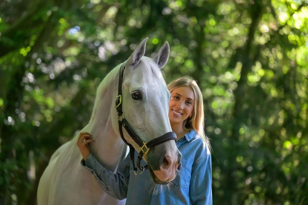 The founder of Crisp Media smiling beside a grey horse in the woods