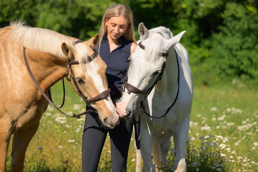 The founder of Crisp Media with a palomino and a grey horse in a summer meadow