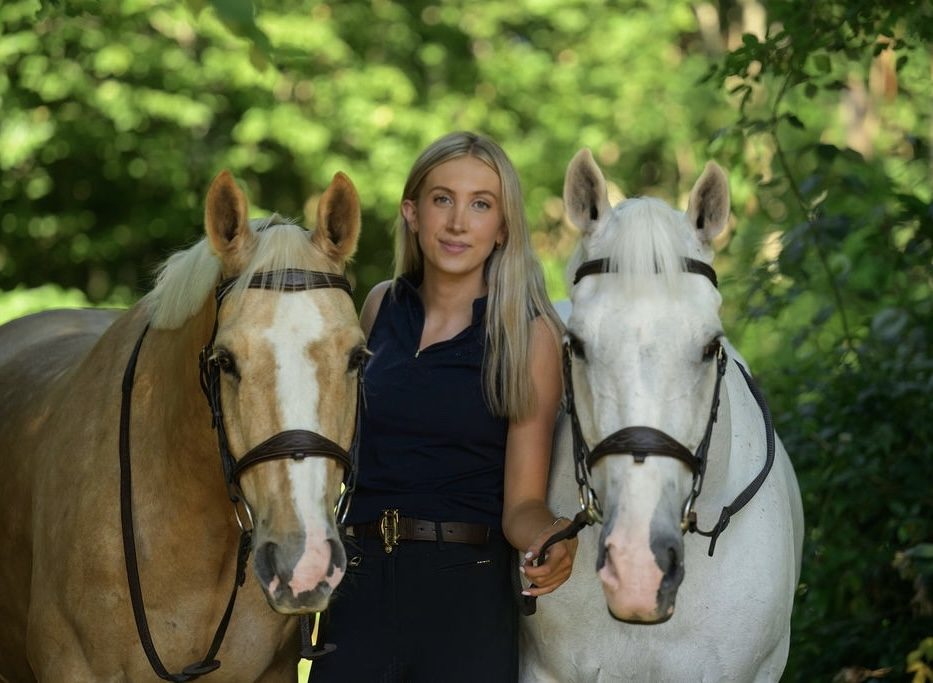 Standing between a palomino and a grey horse