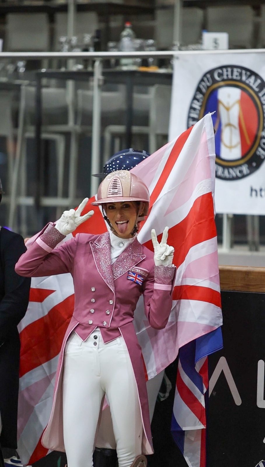 A rider in a sparkling pink tailcoat celebrating in front of a Union Jack